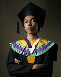 Portrait of man with arms crossed standing against wall