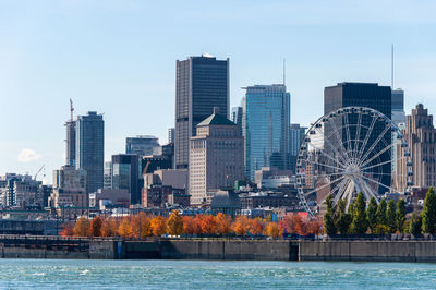 Buildings by river against sky in city