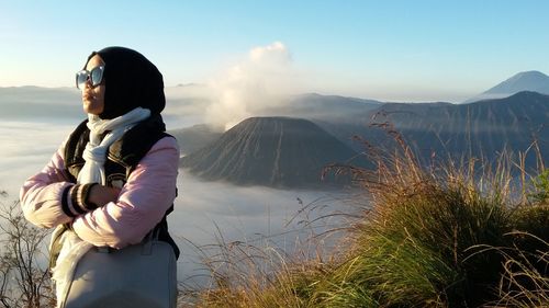 Side view of woman standing against mountain during sunset