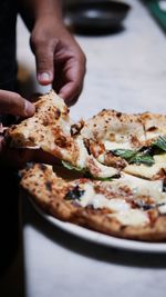 Cropped hand of man holding pizza on table