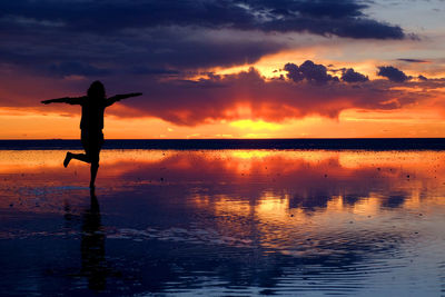 Silhouette woman on on salt lake during sunset