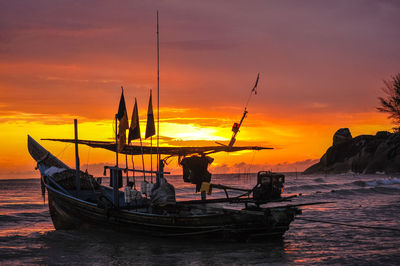 Boat in sea against orange sky