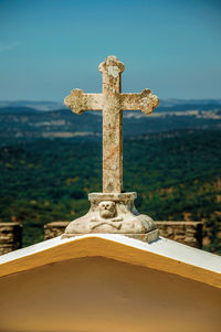 Close-up of cross at cemetery against sky