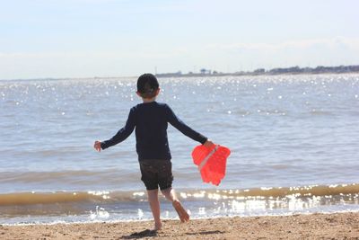 Full length of boy standing on beach against sky