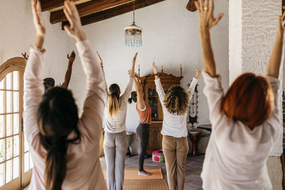 Friends and yoga instructor stretching hands in yoga studio