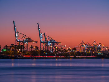 Illuminated commercial dock against sky during sunset