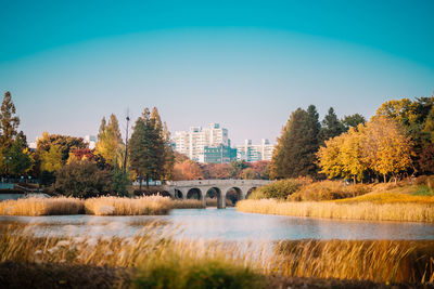 Arch bridge over river against clear sky during autumn