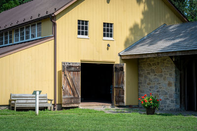 A historical yellow barn with the barn doors open.