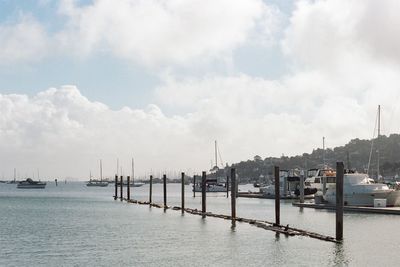 Boats in sea against cloudy sky