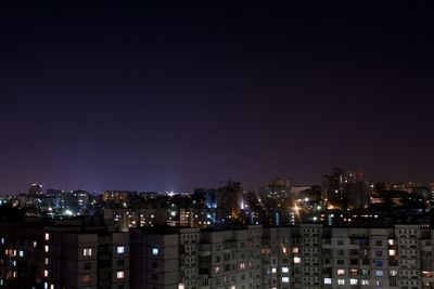 Illuminated buildings in city against clear sky at night