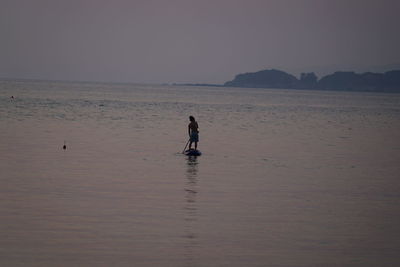 Man standing on beach against clear sky during sunset