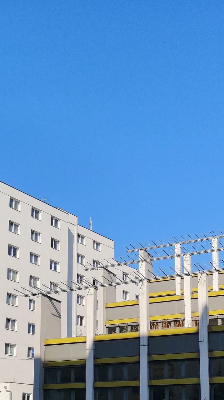 sky, built structure, architecture, clear sky, blue, copy space, building exterior, nature, building, low angle view, day, no people, sunlight, city, outdoors, cable, electricity, public transportation, residential district, fuel and power generation