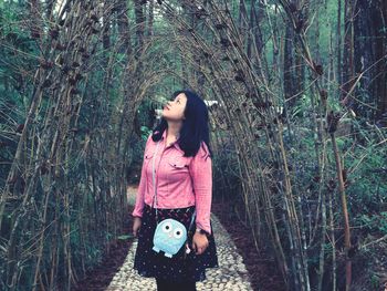 Woman standing by tree trunk in forest