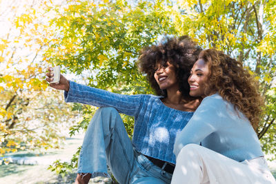 Close up of two female afro american friends with blue jumper smiling while taking selfie