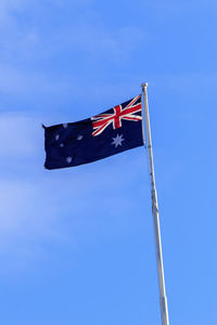 Low angle view of flag against blue sky