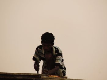 Man couching on roof against sky