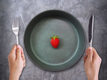 Directly above shot of hand holding strawberry over white background