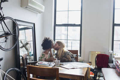 A young couple kissing at a dining table