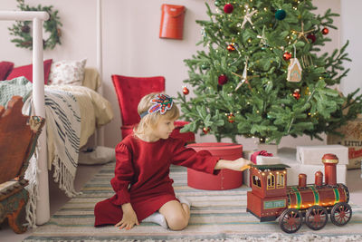 Girl sitting at by christmas tree at home