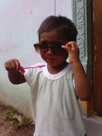 Boy in sunglasses brushing teeth outside door