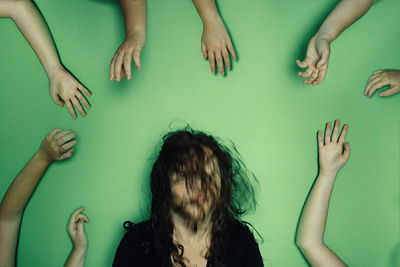 Blurred motion of woman surrounded by hands against green background