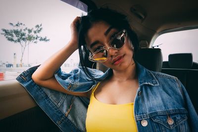 Portrait of young woman holding sunglasses