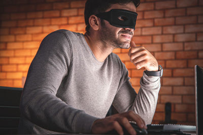 Midsection of man using smart phone against wall