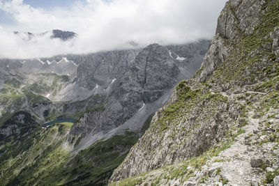 Scenic view of lake and rocky mountains against cloudy sky