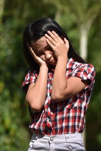 Girl holding head in hands outdoors