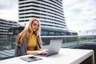 Portrait of woman using laptop while sitting at airport