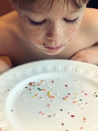 Close-up of boy looking at sprinkles in plate