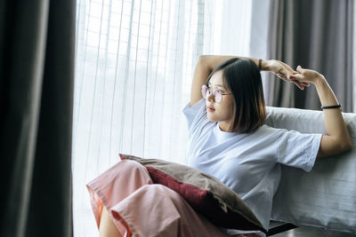 Young woman sitting on window at home