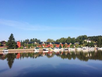 Scenic view of lake by buildings against blue sky