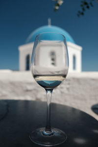 Close-up of wineglass on beach against clear blue sky