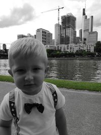 Portrait of boy in city against sky