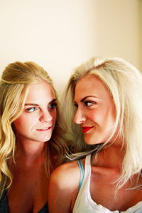 Close-up of female friends looking at each other against wall