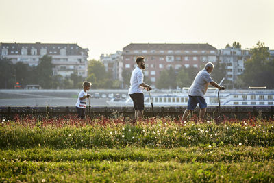 Grandfather, father and son riding scooters at the riverside