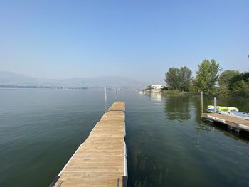 Pier over lake against clear blue sky