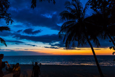 Silhouette palm trees on beach against sky during sunset