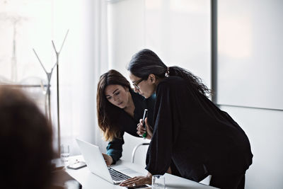 Female entrepreneurs discussing over laptop at conference table in board room