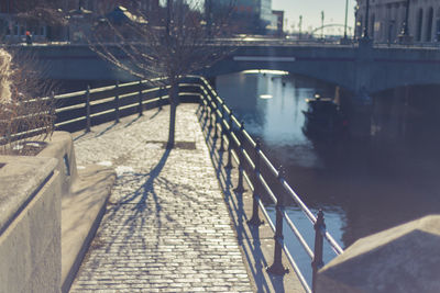 Footbridge over river in city during winter