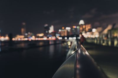 Illuminated city by river against sky at night