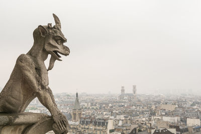 Statue in city against clear sky