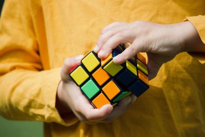 Midsection of boy playing with puzzle cube