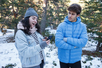 Happy friends standing on snow covered land