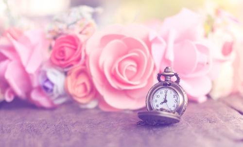 Close-up of pocket watch with flower decorations on table