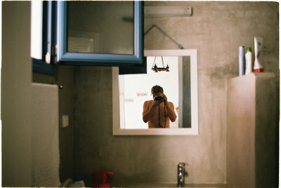 Rear view of woman standing in bathroom