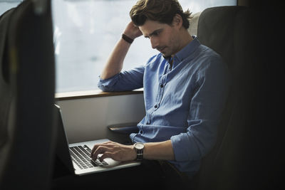 Businessman using laptop while traveling in train