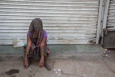 Homeless woman sitting outside closed shop