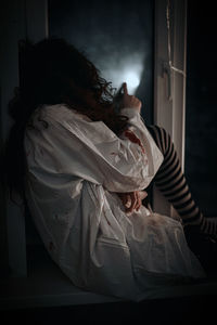 Rear view of girl sitting at home